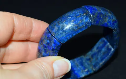 Błękitna bransoleta z lapis lazuli, z widocznymi złotymi inkluzjami pirytu, prezentowana na dłoni.