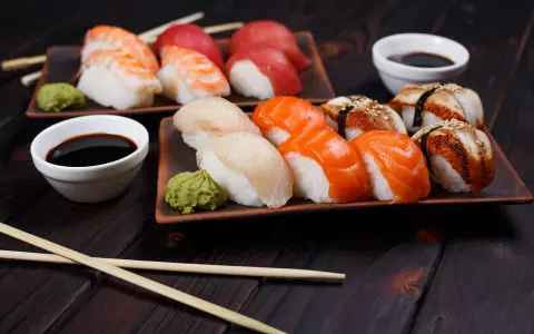 Różnorodne rodzaje sushi: nigiri z krewetką, łososiem, białym rybą i węgorzem, podane z wasabi i sosem sojowym.