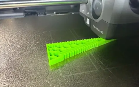 Drukarka 3D tworzy zielony obiekt z filamentu TPU, pokazując jego elastyczne właściwości.