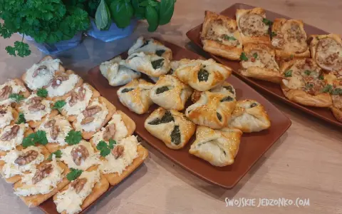 Na stole trzy rodzaje przekąsek: krakersy z pastą serową i orzechami, pieczone ciastka z nadzieniem szpinakowym i kwadratowe tartaletki z farszem. Idealna szybka przekąska na imprezę.