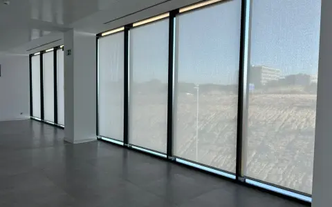Ventanas con tejido screen que filtran la luz, creando un ambiente sereno en la oficina.