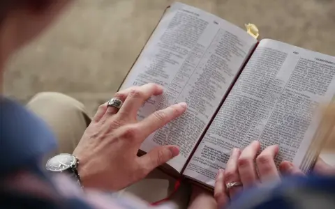 Dłonie pary przeglądają Biblię, szukając pocieszenia i siły przeciwko złemu duchowi.