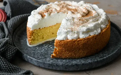 Tarta tres leches esponjosa, cubierta de merengue y espolvoreada con canela. Se ve deliciosa y lista para disfrutar.