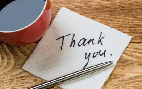 Na serwetce napisano "Thank you". Obok filiżanka kawy i długopis. To jak mail na pożegnanie w pracy.