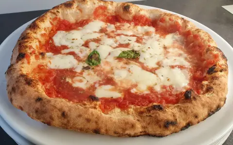 Pizza a lunga lievitazione con pomodoro, mozzarella filante e basilico fresco. Croccante fuori, soffice dentro, un vero capolavoro.