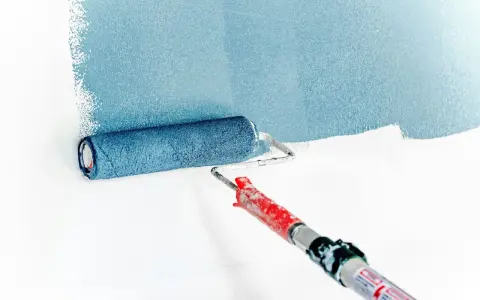 Rodillo aplicando pintura azul sobre pared blanca. La imprimación es el primer paso para un acabado perfecto.