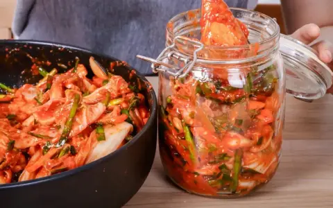 Domowe kimchi w słoiku i misce, przygotowywane z kapusty i przypraw.