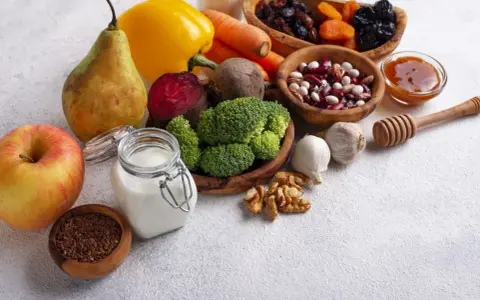 Składniki na zdrową dietę jelitową: jabłko, gruszka, brokuły, buraki, marchew, papryka, fasola, orzechy, czosnek, siemię lniane, jogurt, suszone owoce i miód.