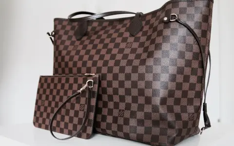 Duża torebka Louis Vuitton w kratkę, obok mniejsza kosmetyczka. Klasyczny wzór Damier Ebene.