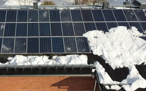 Solpaneler på ett tak med 38 graders taklutning, delvis täckta av snö.