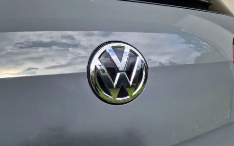 Das VW-Logo auf dem Heck eines grauen Autos. Eine Erklärung zum Fahrzeugdatenträger VW ist hier nicht ersichtlich.