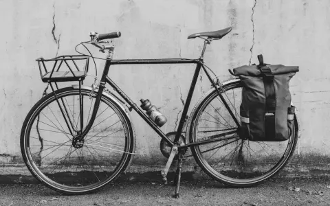 Svart cykel med korg fram och väska bak, redo att montera pakethållare för äventyr.