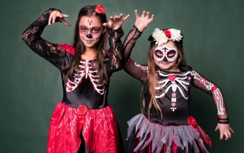 Dwie dziewczynki w strojach szkieletów z makijażem na Dzień Zmarłych. Inspiracja, jak się przebrać na Halloween.