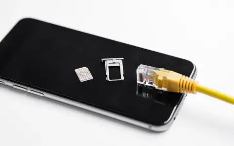 Smartfon z kartą SIM i tacką, podłączony żółtym kablem sieciowym. Możliwość play multisim.
