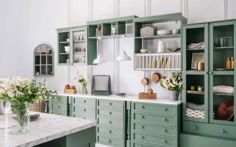 Cucina in stile provenzale casa con mobili verdi, pentole in rame appese e fiori freschi.