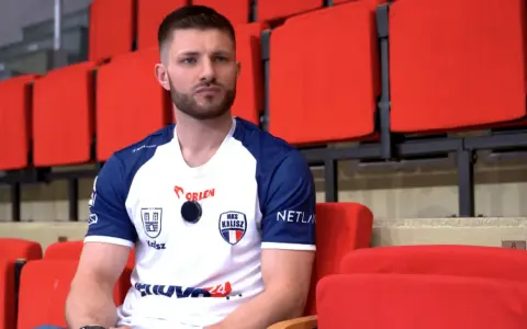 Marcel Sroczyk, zawodnik MKS Kalisz, siedzi na czerwonych trybunach.