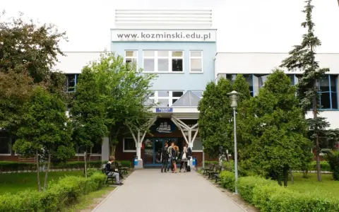Studenci przed budynkiem koźmin uczelnia. W tle logo uczelni i napis www.kozminiński.edu.pl.