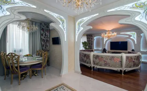Ett lyxigt vardagsrum och matsal i art nouveau jugendstil med blommig soffa, kristallkronor och utsmyckade valv.