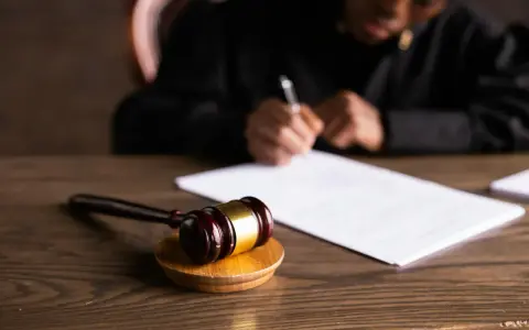 Młotek sędziowski i dokumenty na drewnianym stole, symbolizujące postępowanie egzekucyjne kpc.