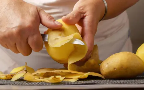Hände schälen Kartoffeln für die Zubereitung. Bald sind die Kartoffeln gar und bereit zum Genuss.