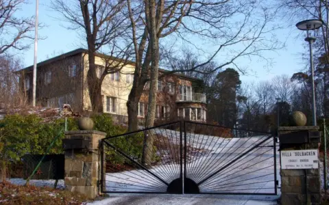 Här bor prins Carl Philip. Villa Solbacken, en vacker byggnad med en imponerande grind, omgiven av träd och snö.