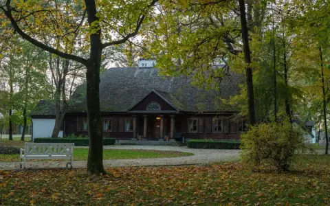 Jesienny dworek w Radziejowicach, otoczony drzewami i opadłymi liśćmi. Idealne miejsce na spokojny spacer i odkrywanie lokalnych atrakcji.