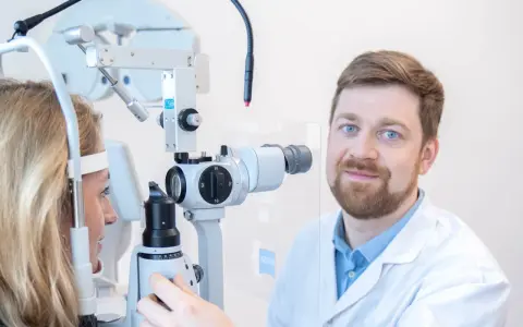Okulista przeprowadza test na nadwzroczność u pacjentki, badając jej wzrok za pomocą specjalistycznego sprzętu.