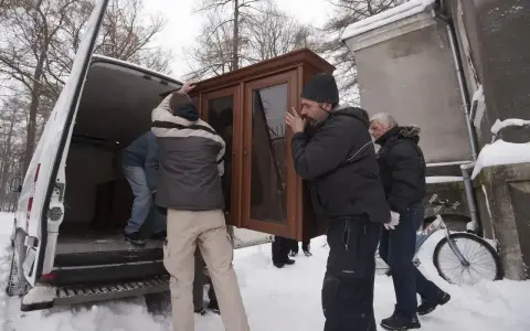 Mężczyźni wynoszą mebel z domu, by uniknąć eksmisji. Zimowa aura i śnieg nie powstrzymują przeprowadzki.