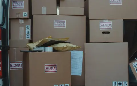 Stos kartonów, w tym oznaczone jako "FRAGILE", gotowych do wysyłki. Czy do reklamacji potrzebny jest karton? Zazwyczaj tak, aby zabezpieczyć towar.