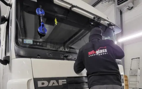 Montaż szyby w traktorze DAF. Pracownik firmy "Autoglass Łukaszewski" używa przyssawek do bezpiecznego osadzenia nowej szyby.