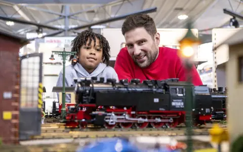Vater und Sohn bestaunen detailreiche Modelleisenbahnen auf der Modellbaumesse Dortmund.