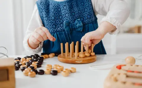 Niña con vestido azul jugando con cuentas de madera y un juego de encaje, parte de juegos para superar el mutismo selectivo.