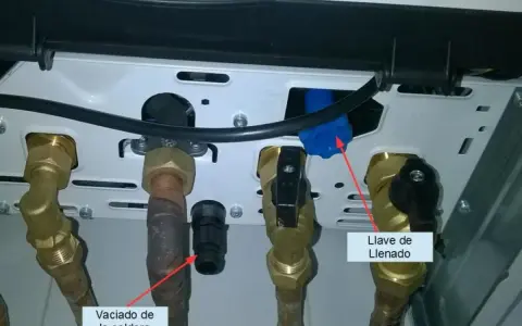 Detalle de conexiones de caldera. Flecha roja señala "Vaciado de la caldera" y otra flecha roja indica "Llave de Llenado".
