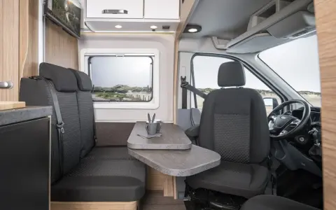 Interiör i husbil med sittgrupp, bord och förarplats. Kanske ett problem med kabe husbilar kan lösas med denna smarta planlösning.