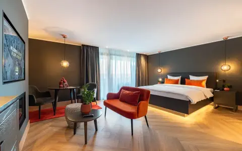 Modern Hotelzimmer mit großem Bett, orangefarbenem Sofa und Sitzbereich.