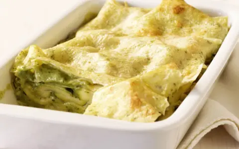 Zucchini-Lasagne mit cremiger Füllung und goldbraunen Lasagneplatten in einer weißen Auflaufform.