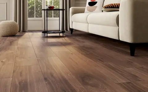 Un salon lumineux avec un nouveau revêtement sol en bois chaleureux, un canapé crème et des coussins décoratifs.