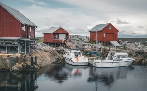 Norwegia: praca w norwegii dla par z zakwaterowaniem. Czerwone domki rybackie i łodzie przy skalistym brzegu.