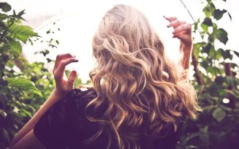 Frau mit welligem Haar, das einen subtilen Reverse Balayage-Effekt zeigt. Vorher-Nachher-Verwandlung für einen natürlichen Look.