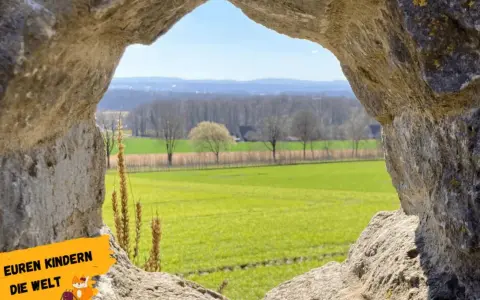 Blick durch eine Felsöffnung auf grüne Felder und Bäume. Perfekt für Ausflugsziele OWL mit Kindern, um die Natur zu entdecken.