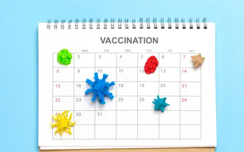 Kalendarz z napisem "VACCINATION" i kolorowymi modelami wirusów na dniach. Planowanie szczepień to klucz do pokonania pandemii.