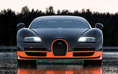 Czarny Bugatti Veyron z pomarańczowymi akcentami, gotowy do jazdy po mokrej nawierzchni.