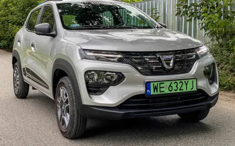 Srebrna Dacia Spring z zieloną tablicą rejestracyjną WE 632YJ, przód samochodu.