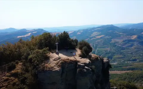 Due escursionisti celebrano la vetta raggiunta sul crinale, un momento clou del cammino della Via degli Dei in 5 giorni.