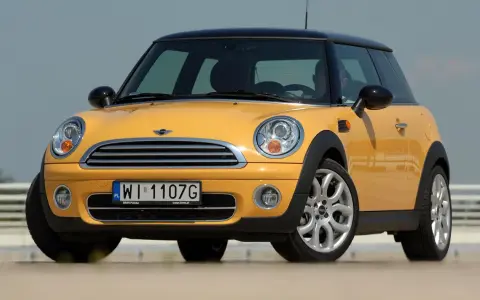 Żółty Mini Cooper, jedna z nowszych generacji, z czarnym dachem i felgami.