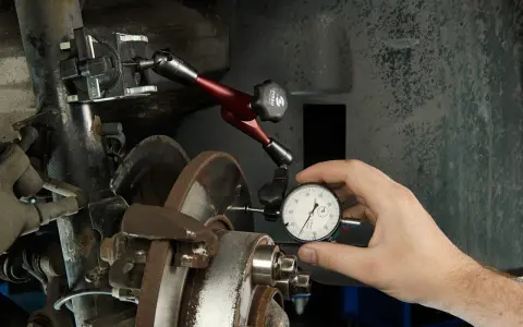 Mechanik mierzy bicie przy hamowaniu z dużej prędkości za pomocą czujnika zegarowego.