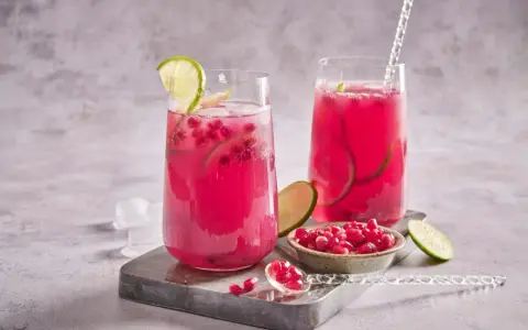 Cocktail fruité et rafraîchissant, ce cocktail fruit du dragon est garni de quartiers de citron vert et de graines de grenade.