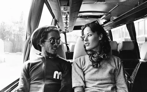 Bob Marley i Kate Marley w autobusie, patrzą na siebie z uśmiechem.