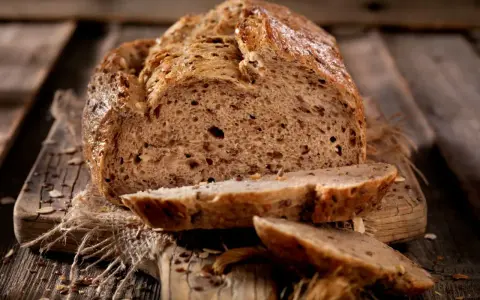 Frisch gebackenes Körnerbrot, angeschnitten auf einem Holzbrett. Perfekt, wann Brot aus der Form nehmen, um diese Kruste zu erhalten.