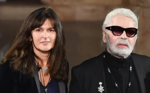 Karl Lagerfeld, iconico stilista Chanel, con una donna dai capelli scuri e un sorriso discreto.